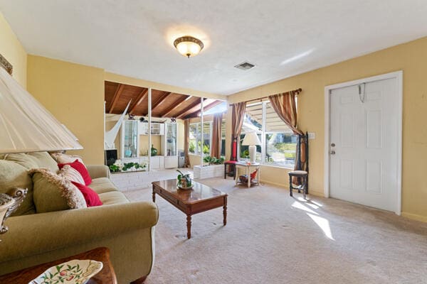 living room featuring carpet flooring, visible vents, baseboards, and lofted ceiling
