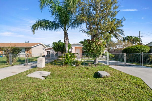 view of front of home with fence, a front yard, driveway, and a gate