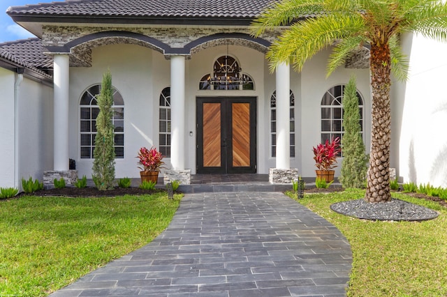 19361 W Sycamore Dr, The Acreage, FL 33470 - view of exterior entry featuring a tiled roof, french doors, and stucco siding