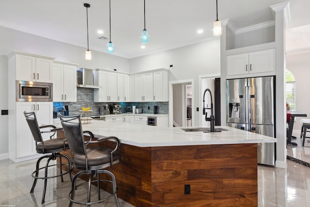 19361 W Sycamore Dr, The Acreage, FL 33470 - kitchen featuring tasteful backsplash, wall chimney exhaust hood, appliances with stainless steel finishes, a large island with sink, and a sink