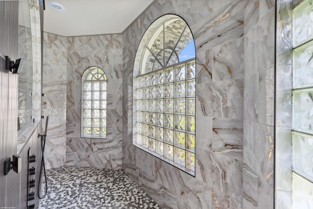 19361 W Sycamore Dr, The Acreage, FL 33470 - bathroom with a healthy amount of sunlight, vanity, tiled shower, and tile walls