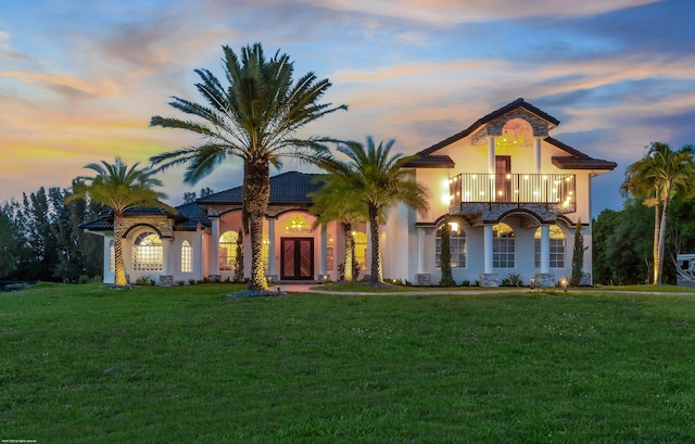 19361 W Sycamore Dr, The Acreage, FL 33470 - mediterranean / spanish house featuring a front yard, a balcony, a tiled roof, and stucco siding