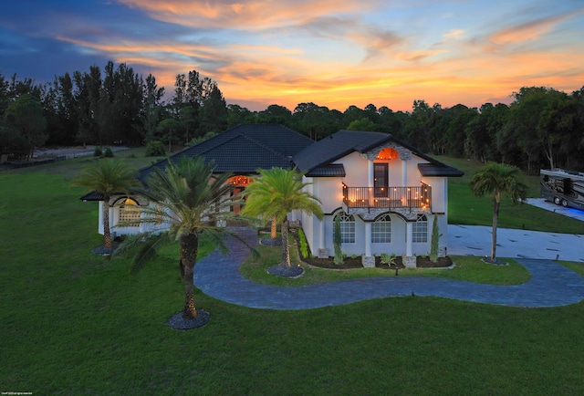 19361 W Sycamore Dr, The Acreage, FL 33470 - view of front of house featuring a yard, stucco siding, curved driveway, and a balcony