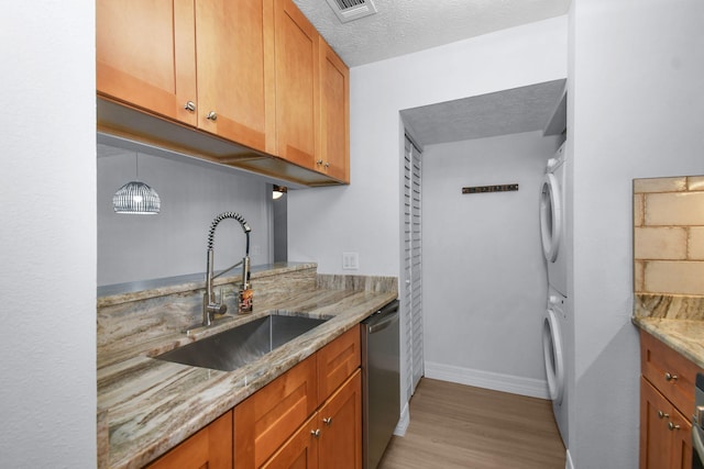 6551 SE Federal Hwy Unit 203, Stuart, FL 34997 - kitchen featuring a sink, stacked washer / drying machine, light wood-style floors, stainless steel dishwasher, and light stone counters
