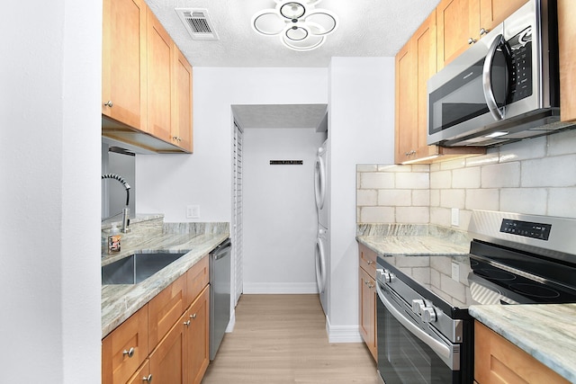 6551 SE Federal Hwy Unit 203, Stuart, FL 34997 - kitchen featuring backsplash, stacked washer / dryer, visible vents, stainless steel appliances, and a sink