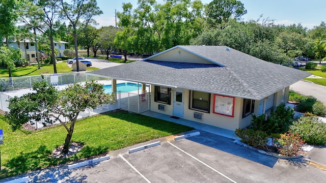 6551 SE Federal Hwy Unit 203, Stuart, FL 34997 - view of front facade with uncovered parking, stucco siding, a front lawn, fence, and a shingled roof