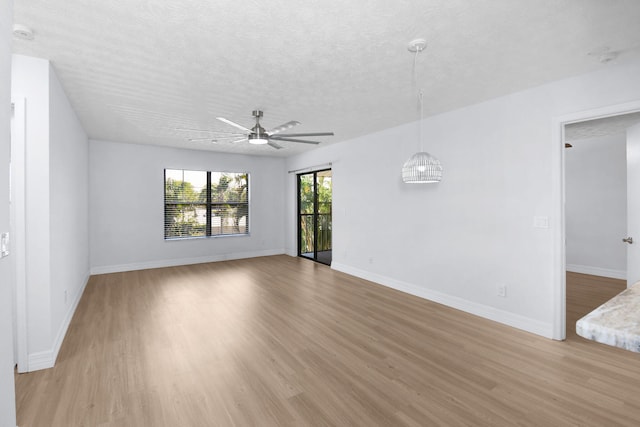 6551 SE Federal Hwy Unit 203, Stuart, FL 34997 - unfurnished living room featuring a textured ceiling, light wood finished floors, baseboards, and a ceiling fan