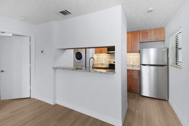 6551 SE Federal Hwy Unit 203, Stuart, FL 34997 - kitchen featuring visible vents, brown cabinets, stainless steel appliances, backsplash, and light wood-style flooring