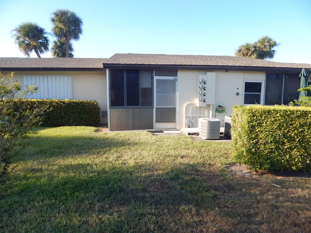 2970 E Ashley Dr E Unit B, West Palm Beach, FL 33415 - back of house featuring stucco siding, a lawn, and central air condition unit