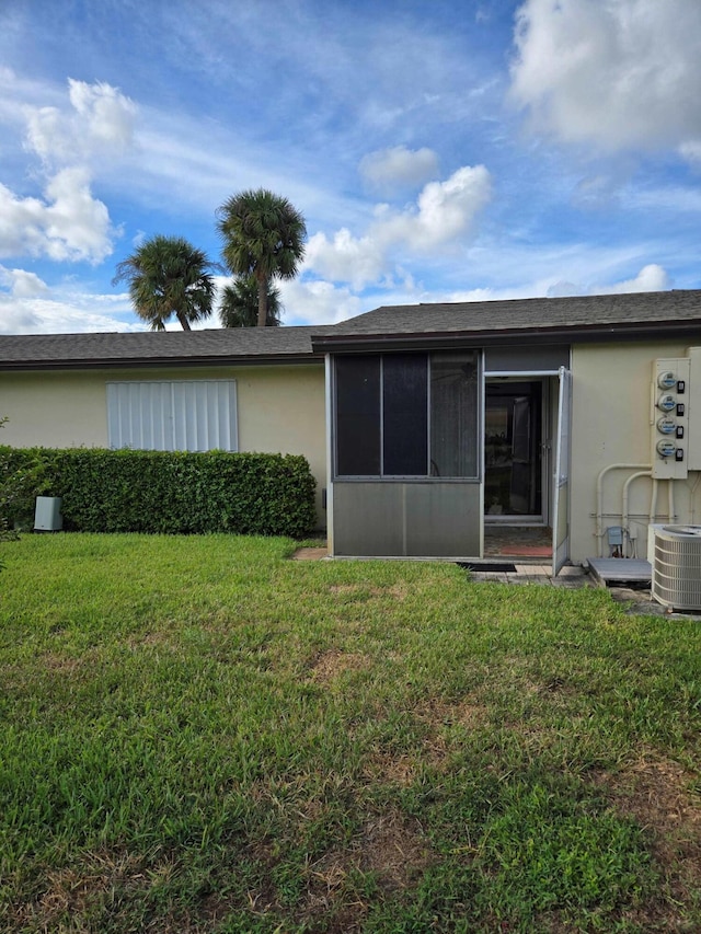 2970 E Ashley Dr E Unit B, West Palm Beach, FL 33415 - back of house featuring stucco siding, central AC, and a lawn