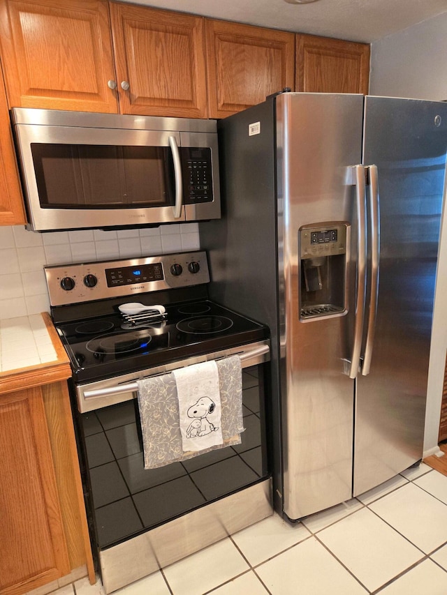 2970 E Ashley Dr E Unit B, West Palm Beach, FL 33415 - kitchen with stainless steel appliances, tile counters, and brown cabinetry