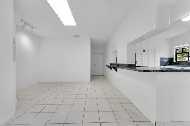 3682 W 2nd Ave, Hialeah, FL 33012 - kitchen featuring dark stone counters, a textured ceiling, and a peninsula