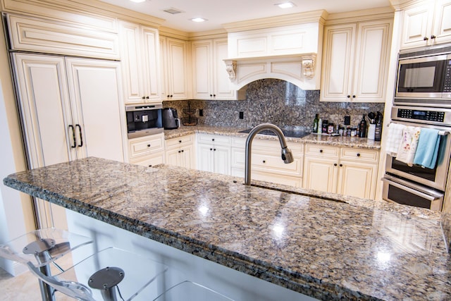 200 E Palmetto Park Rd Unit 503, Boca Raton, FL 33432 - kitchen with dark stone countertops, a sink, decorative backsplash, a breakfast bar, and built in appliances