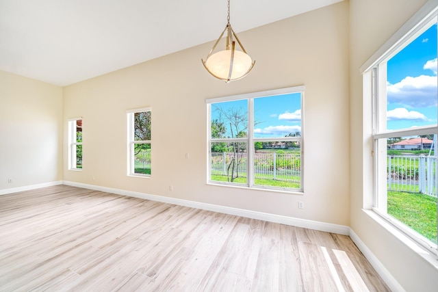 empty room featuring high vaulted ceiling, light wood-style floors, and baseboards