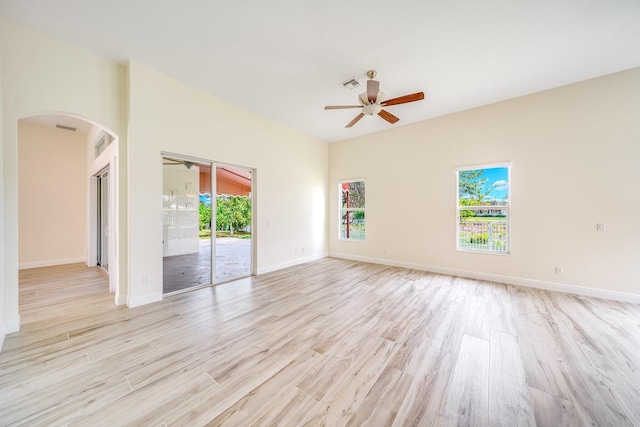 empty room with visible vents, arched walkways, light wood-style floors, baseboards, and ceiling fan