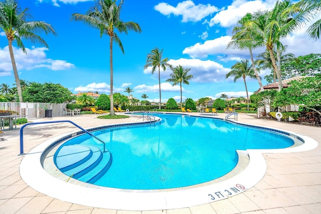 community pool with fence and a patio