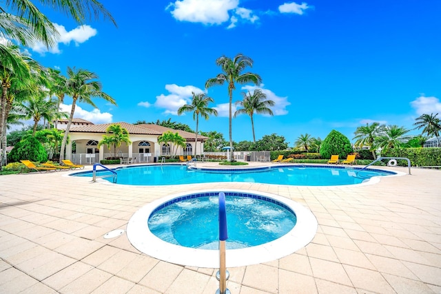 pool with fence, a community hot tub, and a patio