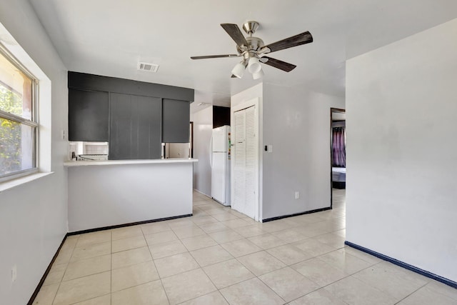 interior space featuring freestanding refrigerator, a ceiling fan, visible vents, light countertops, and dark cabinetry