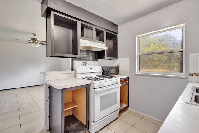 kitchen with open shelves, light countertops, gas range gas stove, under cabinet range hood, and decorative backsplash