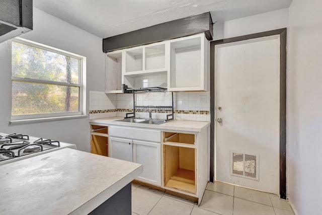 kitchen with tasteful backsplash, light tile patterned floors, open shelves, visible vents, and a sink