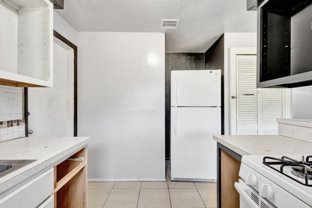 kitchen with light tile patterned floors, visible vents, light countertops, and freestanding refrigerator