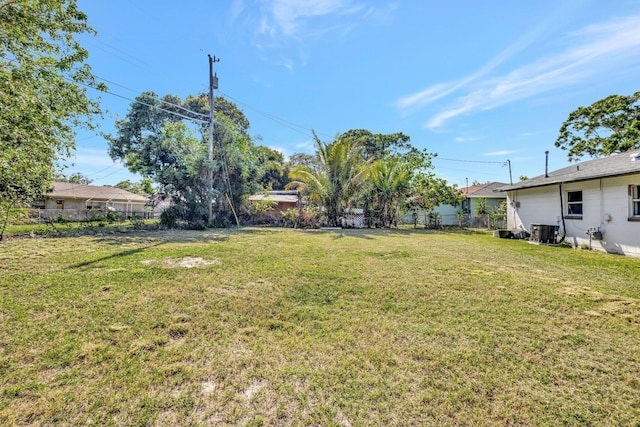 view of yard featuring central AC and fence
