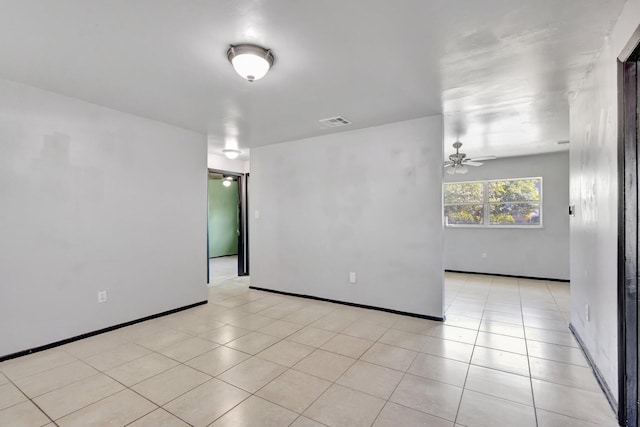 empty room with light tile patterned floors, baseboards, a ceiling fan, and visible vents