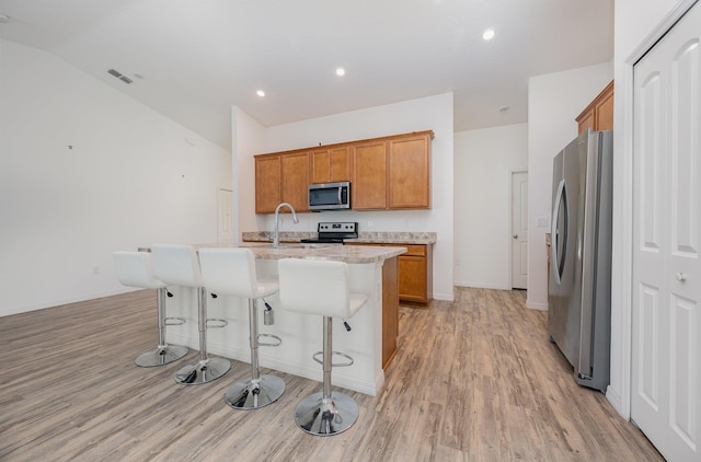 1544 Summit Rd SE, Palm Bay, FL 32909 - kitchen featuring an island with sink, brown cabinetry, stainless steel appliances, light wood-style floors, and visible vents