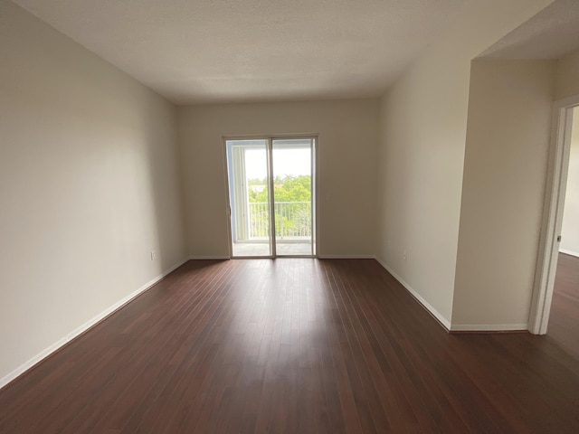 spare room with baseboards and dark wood-style flooring