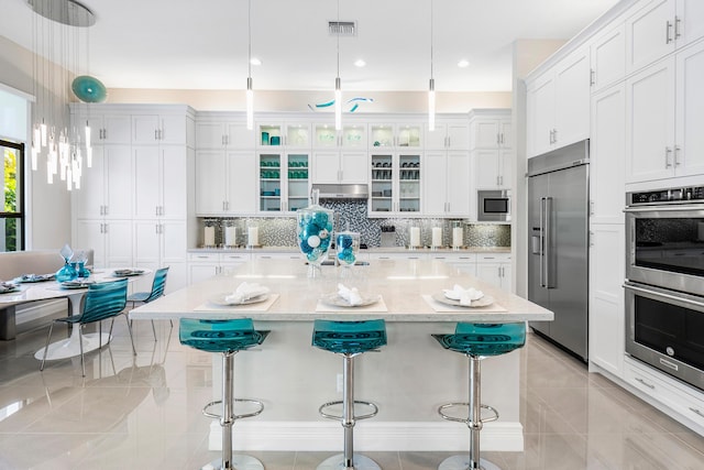 16202 Cabernet Dr, Delray Beach, FL 33446 - kitchen featuring visible vents, white cabinetry, built in appliances, a breakfast bar, and under cabinet range hood