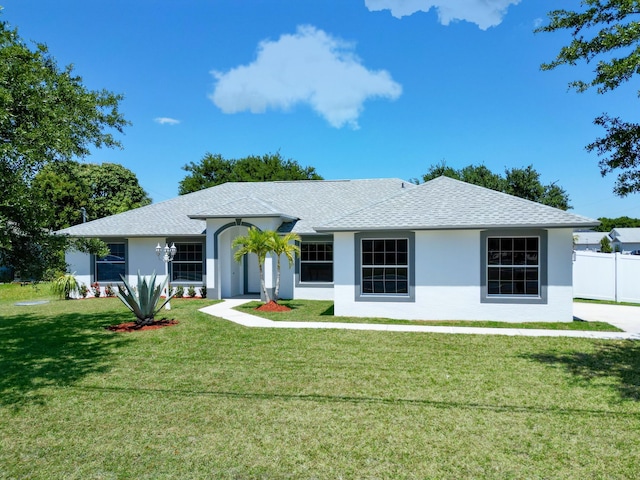 1201 SW Paar Dr, Port Saint Lucie, FL 34953 - ranch-style home with stucco siding, roof with shingles, a front lawn, and fence