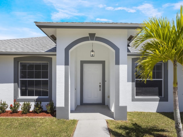 1201 SW Paar Dr, Port Saint Lucie, FL 34953 - property entrance featuring a yard, a shingled roof, and stucco siding