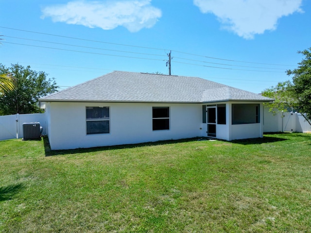 1201 SW Paar Dr, Port Saint Lucie, FL 34953 - back of house with a yard, stucco siding, a fenced backyard, central AC unit, and a shingled roof