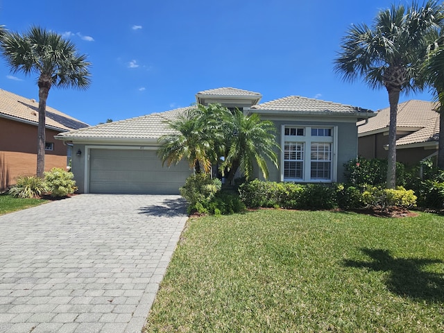 411 NW Stratford Ln, Port Saint Lucie, FL 34983 - view of front facade with a front yard, decorative driveway, a tiled roof, an attached garage, and stucco siding