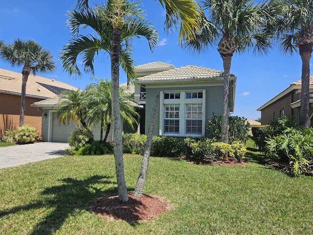 411 NW Stratford Ln, Port Saint Lucie, FL 34983 - mediterranean / spanish home with a front lawn, a tiled roof, an attached garage, decorative driveway, and stucco siding