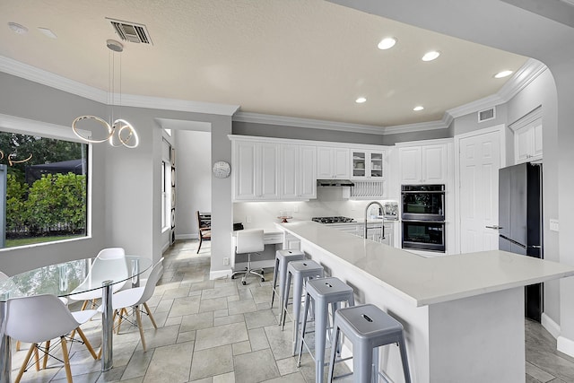 kitchen with freestanding refrigerator, double wall oven, stone tile floors, baseboards, and visible vents