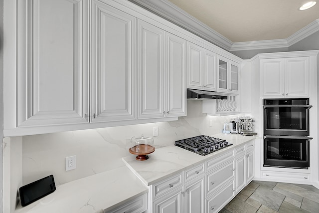 kitchen featuring light stone countertops, black gas cooktop, double wall oven, crown molding, and white cabinetry
