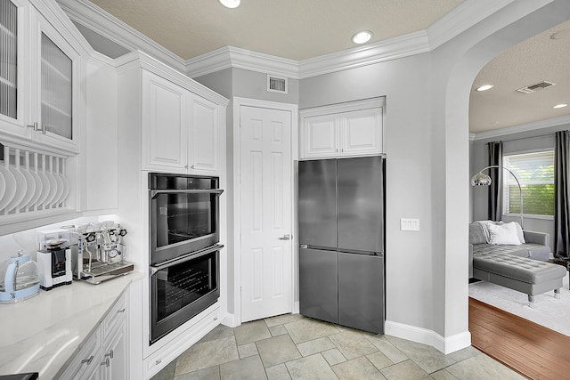 kitchen featuring arched walkways, visible vents, white cabinets, and stainless steel appliances