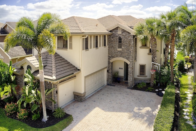 view of front of home with stucco siding, stone siding, decorative driveway, a tiled roof, and an attached garage