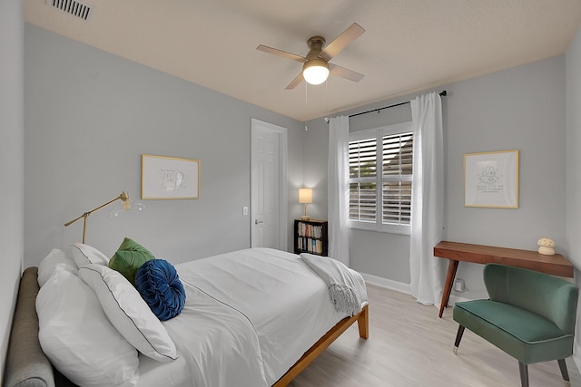 bedroom with baseboards, visible vents, ceiling fan, and light wood finished floors
