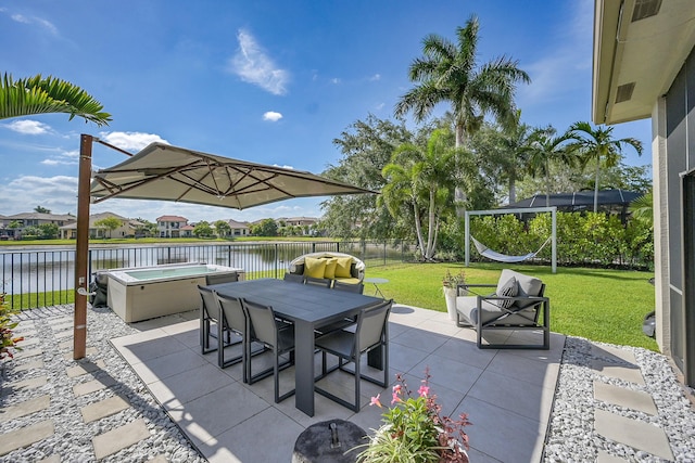 view of patio with a fenced backyard, outdoor dining area, a hot tub, and a water view