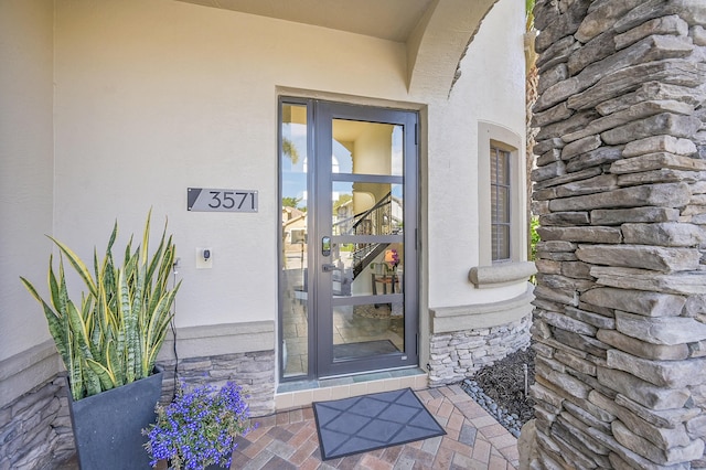 property entrance with stucco siding and stone siding