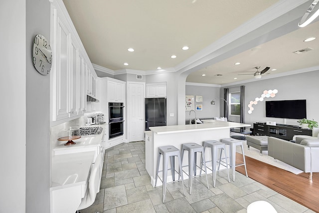 kitchen with a breakfast bar, stainless steel appliances, white cabinets, stone tile floors, and open floor plan
