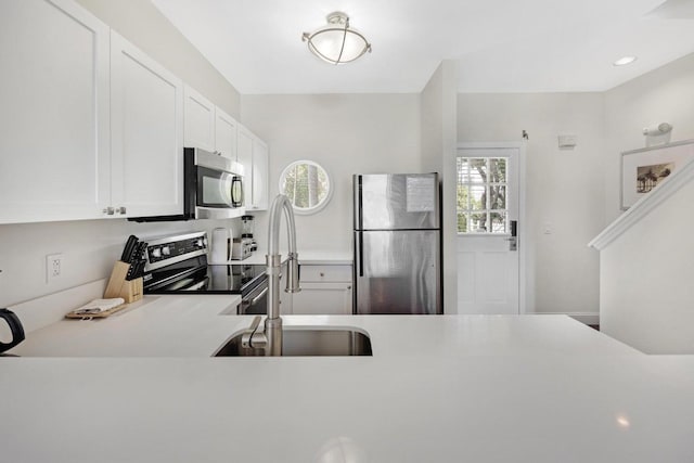 kitchen with white cabinetry, a sink, appliances with stainless steel finishes, light countertops, and recessed lighting