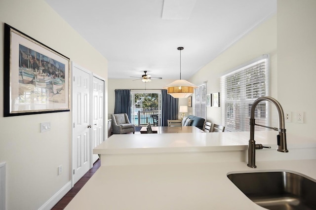 kitchen with a sink, dark wood-type flooring, a ceiling fan, light countertops, and open floor plan