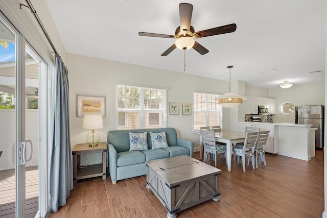 living room featuring visible vents, ceiling fan, light wood finished floors, and baseboards