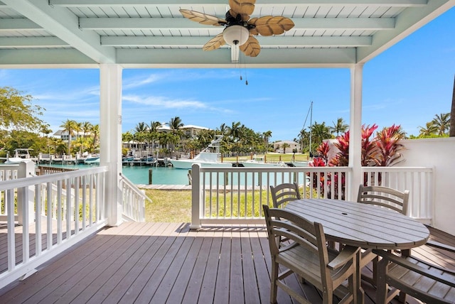wooden deck featuring outdoor dining space, ceiling fan, and a water view
