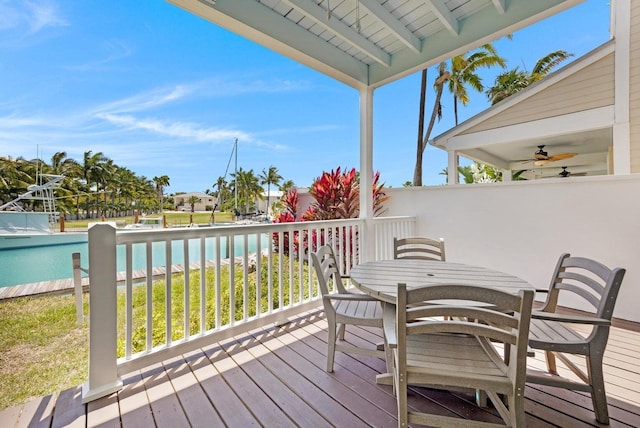 wooden deck with outdoor dining area, a water view, and ceiling fan
