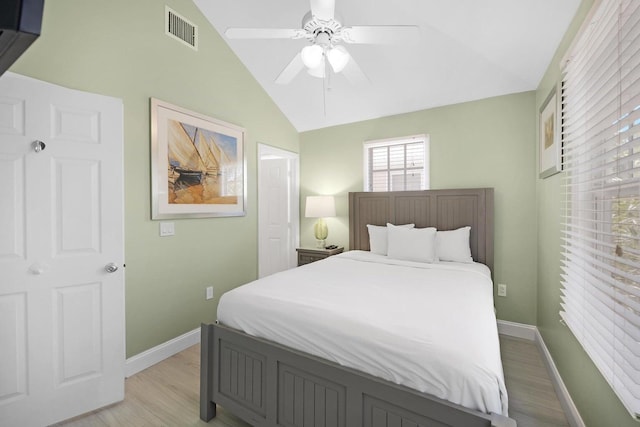 bedroom featuring light wood-style flooring, visible vents, ceiling fan, baseboards, and vaulted ceiling
