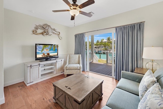 living area featuring visible vents, a ceiling fan, light wood-style flooring, and baseboards